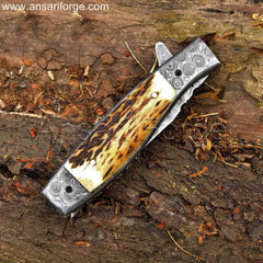 Handmade Damascus steel pocket knife with raindrop pattern, stag antler handle, and genuine leather sheath.