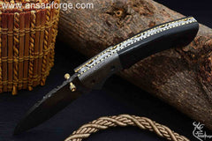 Damascus steel bolsters and file work on brass spine of folding knife.