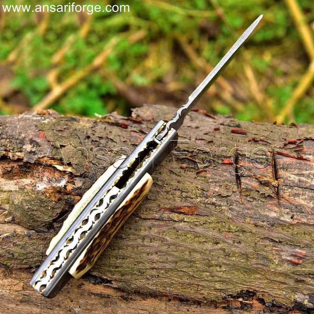 Custom Handmade Damascus steel pocket knife with raindrop pattern, stag antler handle, and leather sheath.