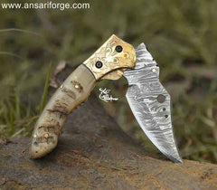 andmade Damascus pocket knife showcasing its smooth liner lock mechanism, engraved bolsters, and unique ram horn handle