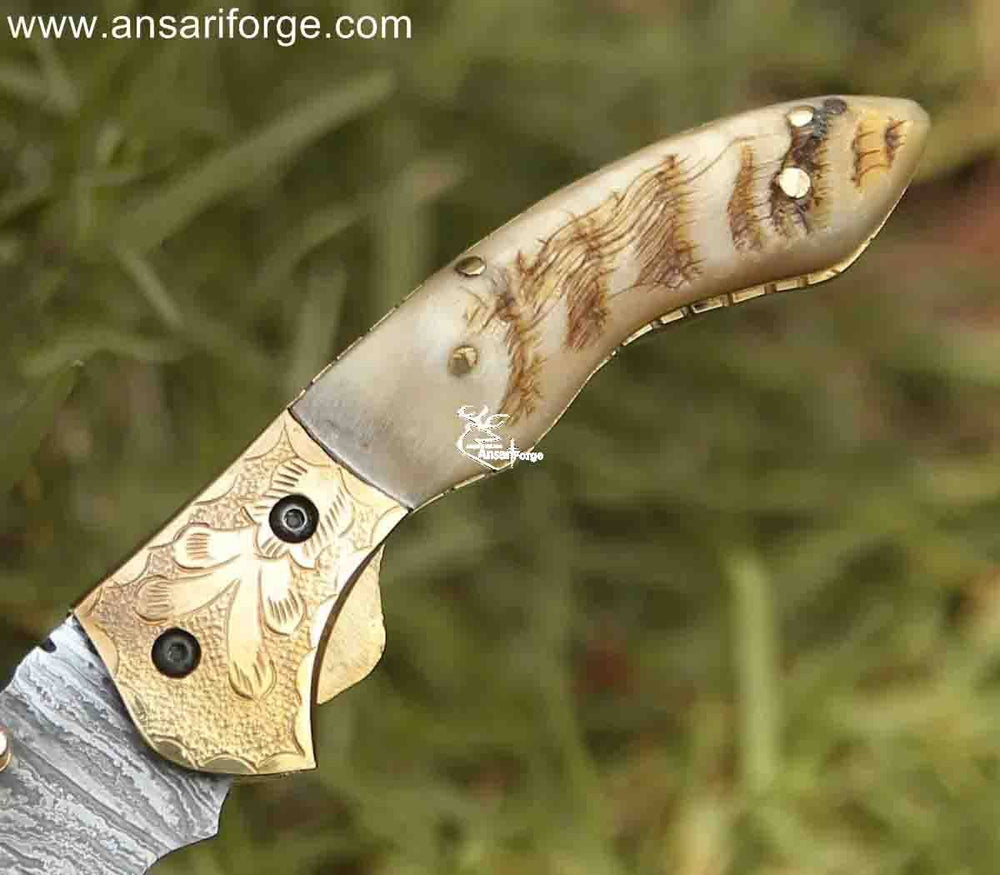 Hand-carved ram horn handle adds a touch of elegance to this Damascus pocket knife featuring engraved bolsters and a secure liner lock