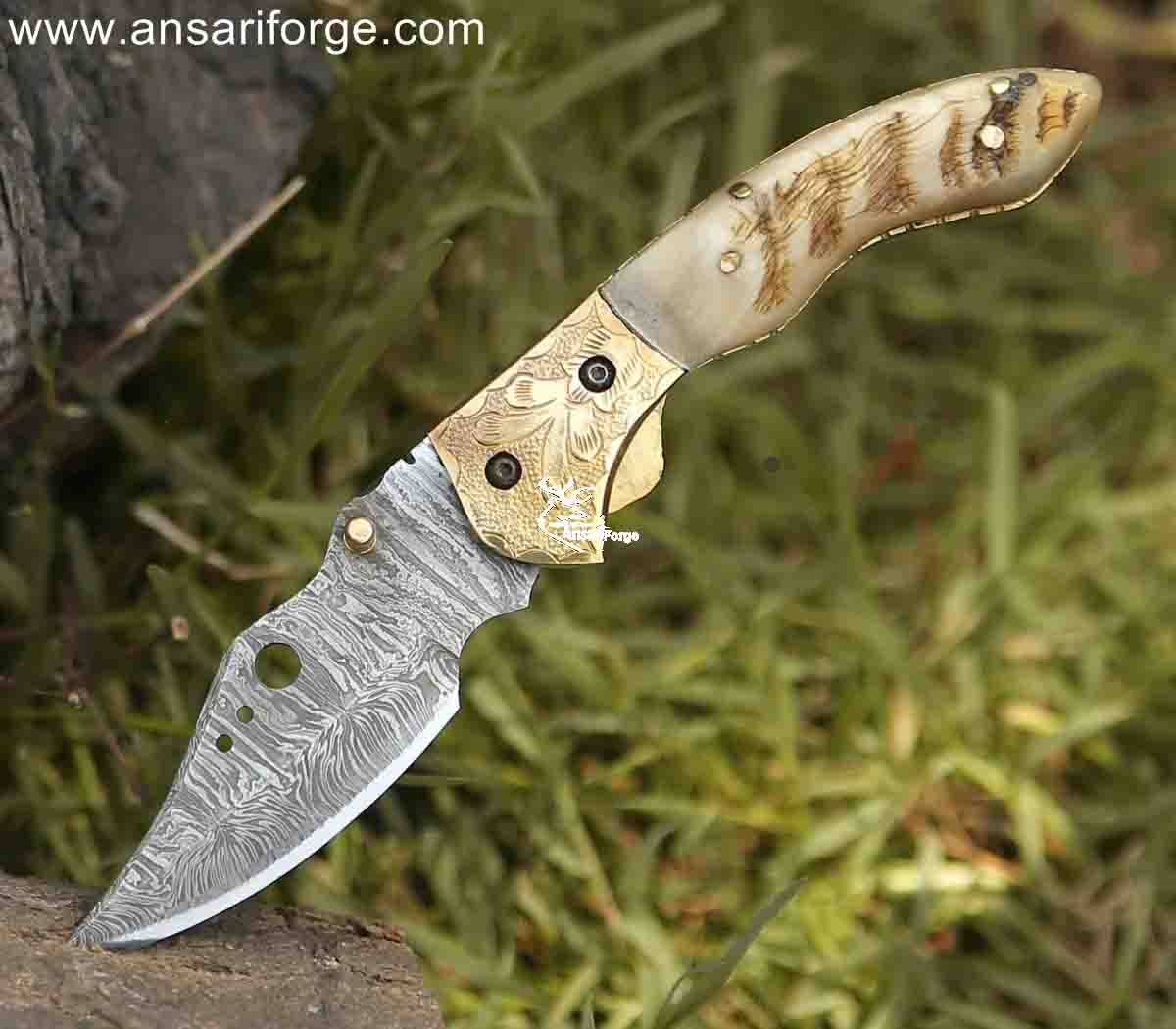 Intricate damask pattern on a handcrafted pocket knife with engraved bolsters and a polished ram horn handle.