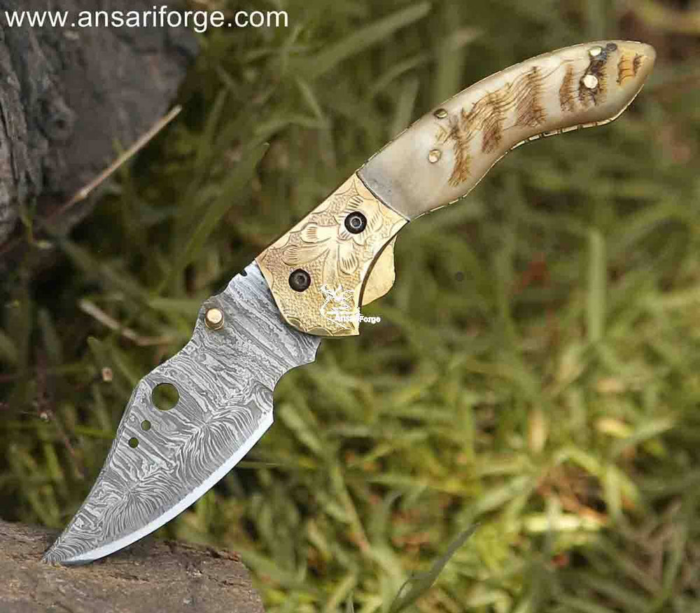 Intricate damask pattern on a handcrafted pocket knife with engraved bolsters and a polished ram horn handle.