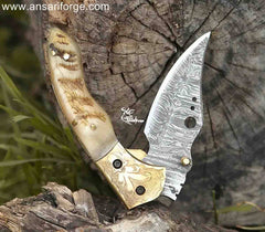 Hand crafted Damascus steel pocket knife featuring a liner lock, engraved bolsters, and a luxurious ram horn handle.