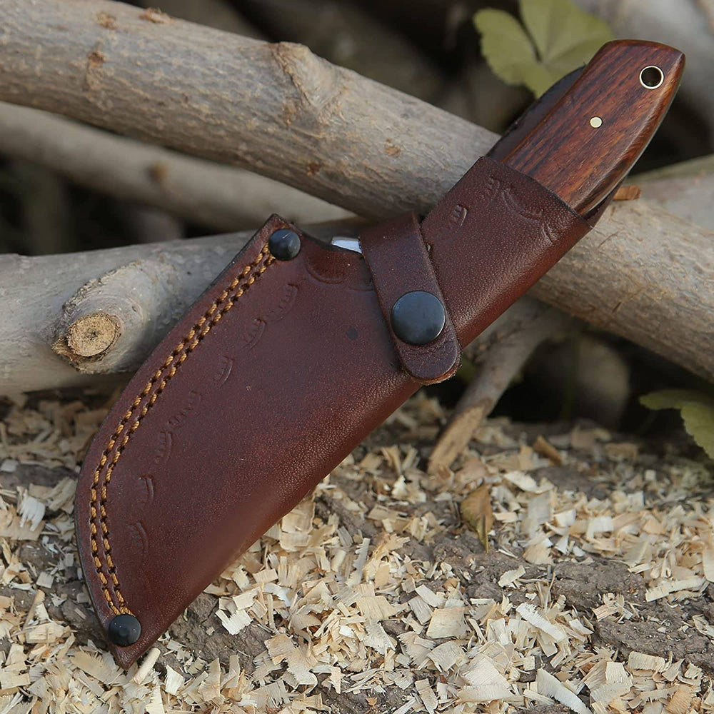Hunting knife with gut hook displayed in its handmade leather sheath, designed for easy belt carry during outdoor adventures.