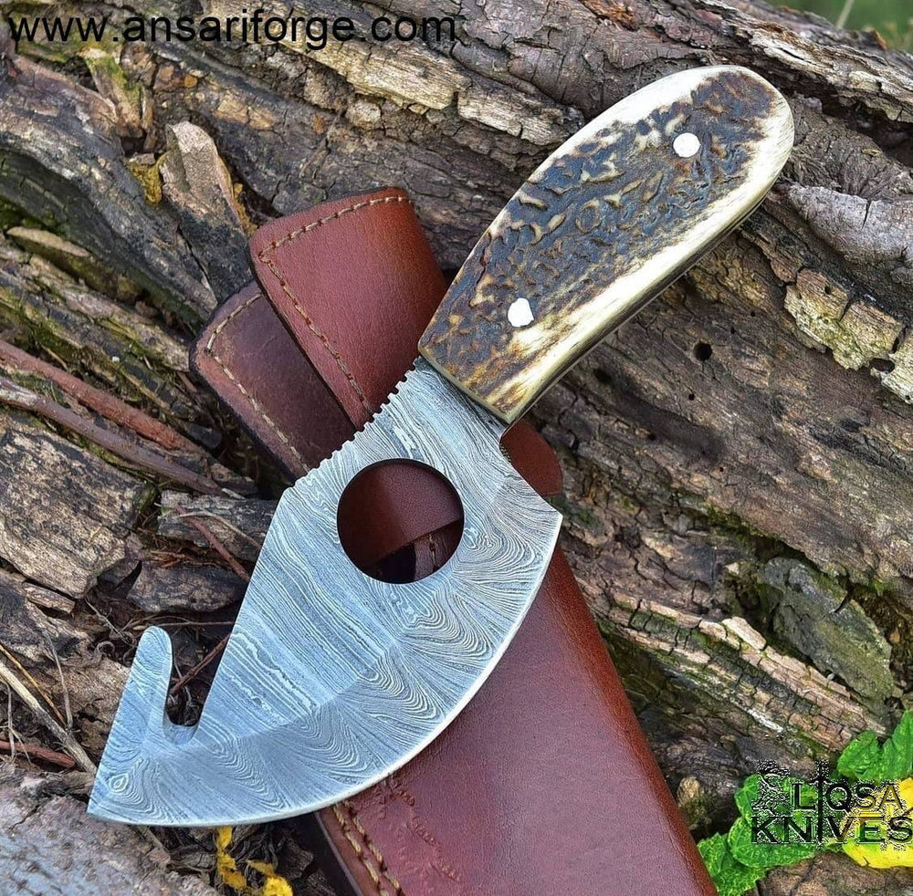Hand-forged Damascus gut hook skinning knife with stag antler handle and leather sheath.