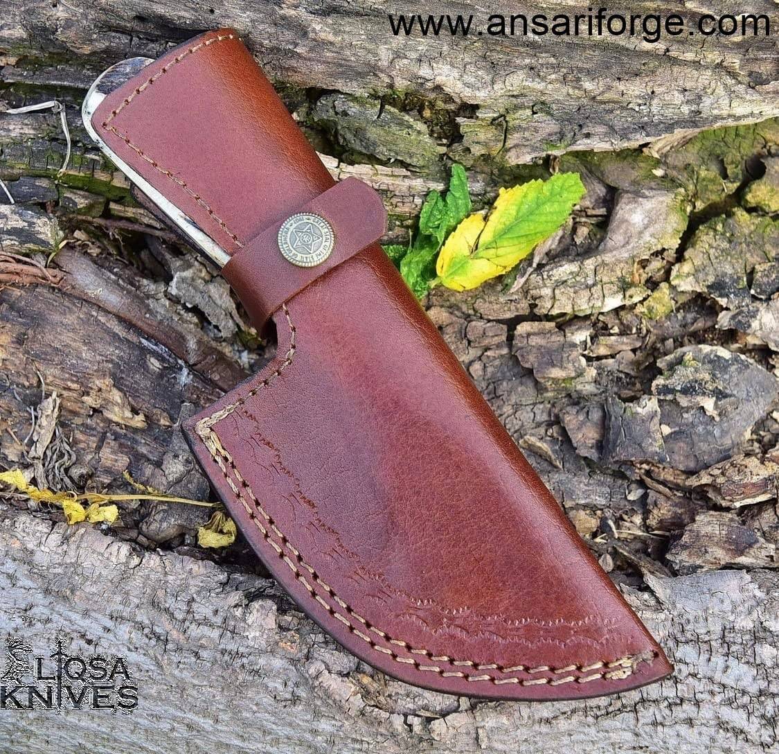 Damascus steel gut hook skinning knife secured in a handmade genuine cowhide leather sheath, ready for outdoor adventures.