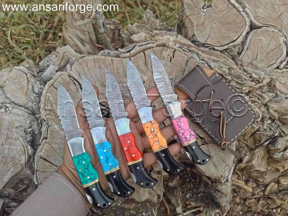 Compact Damascus folding pocket knife set featuring a beautifully patterned blade and a blue turquoise stone handle, resting on a leather surface.