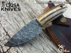 Stag Handle Damascus Knife with a hand-forged raindrop pattern blade, featuring a genuine sambar stag antler handle and a cowhide leather sheath, displayed on a rustic wooden background.