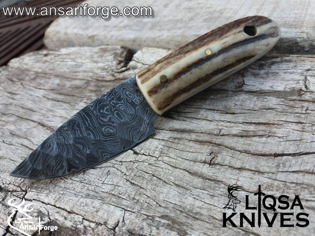 Stag Handle Damascus Knife with a hand-forged raindrop pattern blade, featuring a genuine sambar stag antler handle and a cowhide leather sheath, displayed on a rustic wooden background.
