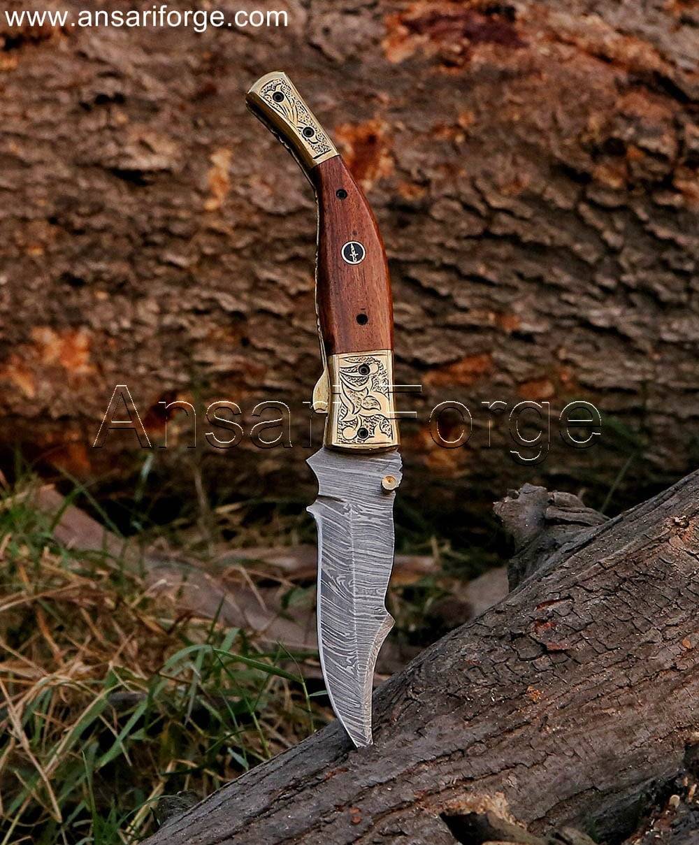 Damascus Folding Knife with a twist pattern blade, walnut wood handle, and engraved brass bolsters, displayed open.