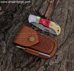 Damascus folding pocket knife with a twist pattern blade, camel bone handle, and cowhide leather sheath.