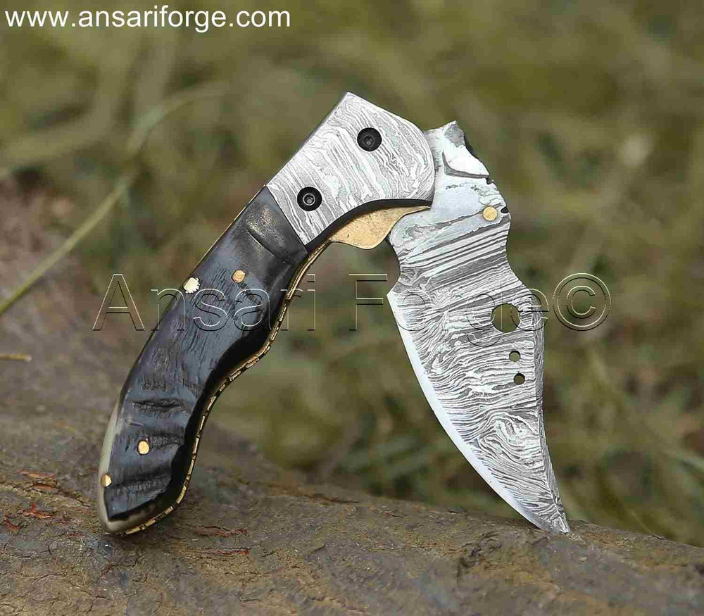 Damascus Pocket Knife by Ansari Forge with a 1095 & 15n20 Damascus steel blade, Himalayan sheep horn handle, and brass frame. Featuring a fire pattern, liner lock mechanism, and leather sheath.