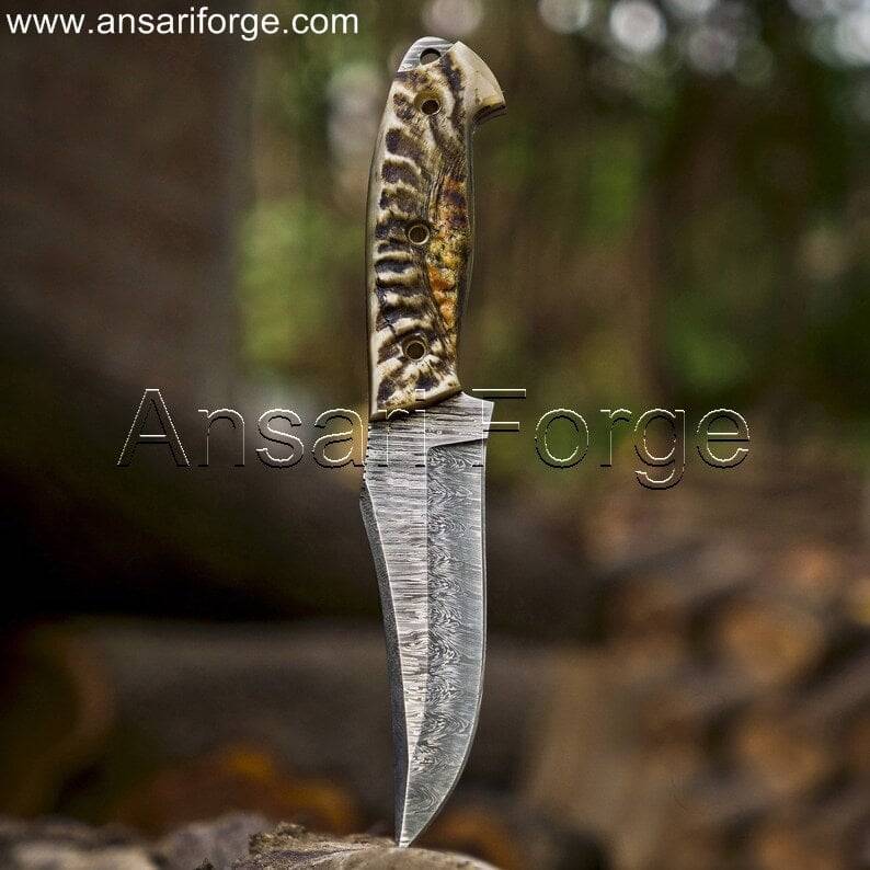 Markhor Hunter Damascus Steel Knife with camping gear, ideal for outdoor adventures.