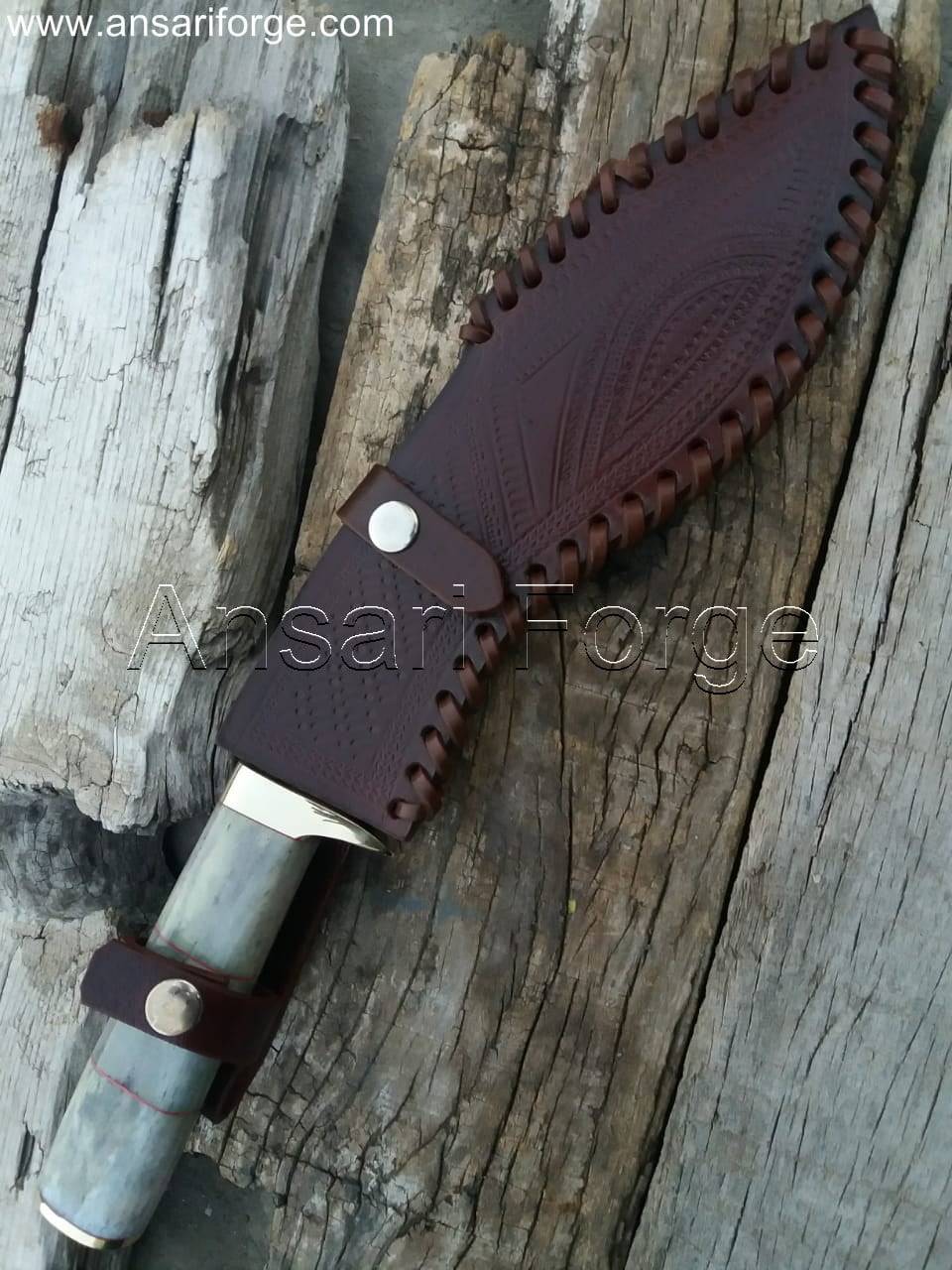 Close-up view of a beautiful Damascus kukri knife with a camel bone handle, leather sheath, and distinct layered blade pattern.