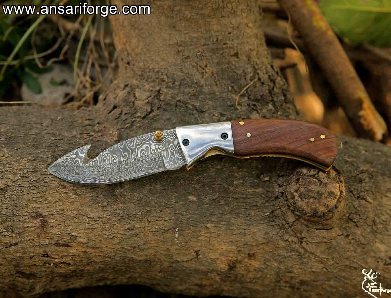 Open folding pocket knife with a 3.25-inch blade and gut hook, highlighting the beautiful layered pattern of the hand-forged Damascus steel.