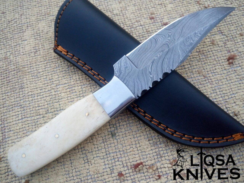Close-up view of the hand-forged Damascus steel blade, highlighting the intricate 512-layer twist pattern and drop point design.